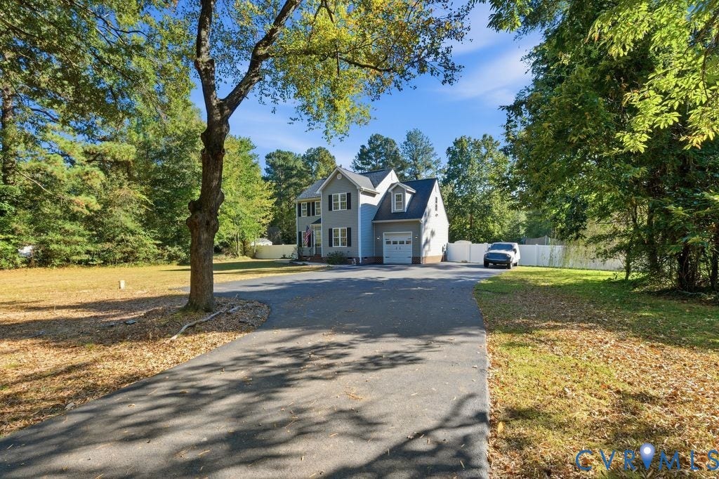 8477 Cheraw Road, Mechanicsville, VA 23116 Two-story exterior featuring light-toned siding, asphalt driveway, single-car attached garage, and surrounding mature trees on a spacious lot