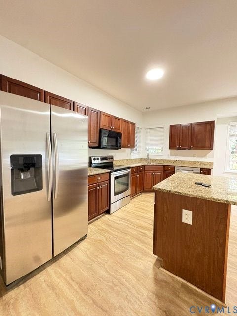 9504 Hungary Woods Drive, Glen Allen, VA 23060 Kitchen featuring wood cabinetry, stone countertops, central island, stainless steel refrigerator, and integrated stainless steel oven and microwave