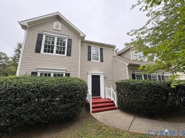 9504 Hungary Woods Drive, Glen Allen, VA 23060 Two-story residence featuring light-toned horizontal siding, dark decorative shutters, a covered red-painted stoop, and a concrete walkway