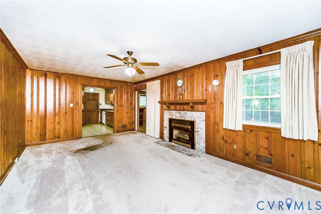 4511 Inca Drive, Ampthill, VA 23237 Living area featuring wood paneling, a fireplace with a light-toned masonry surround, a wooden mantel, and a ceiling-mounted light fixture with a fan