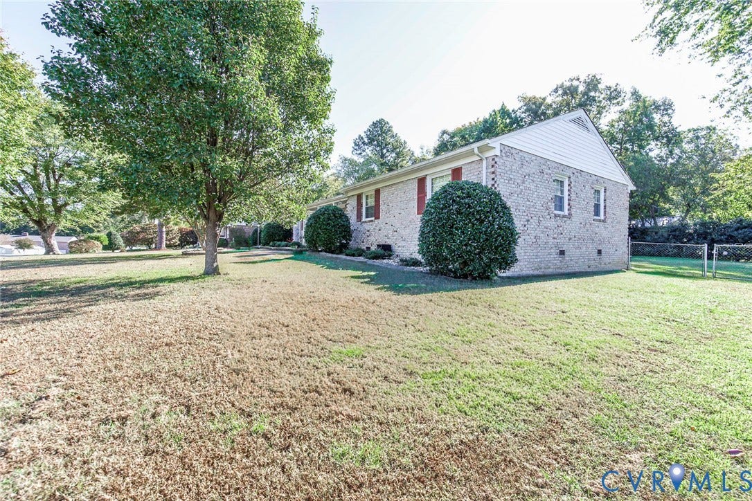 4511 Inca Drive, Ampthill, VA 23237 Brick exterior featuring vinyl gables, window shutters, and an expansive lawn with mature trees