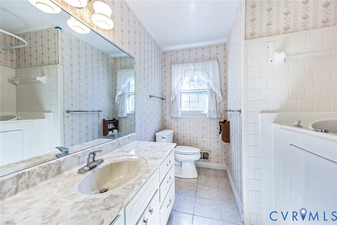 4511 Inca Drive, Ampthill, VA 23237 Full-width vanity with stone-finish countertop, integrated sink, expansive wall-mounted mirror, ceramic tile flooring, and tub-shower combination with ceramic wall surround
