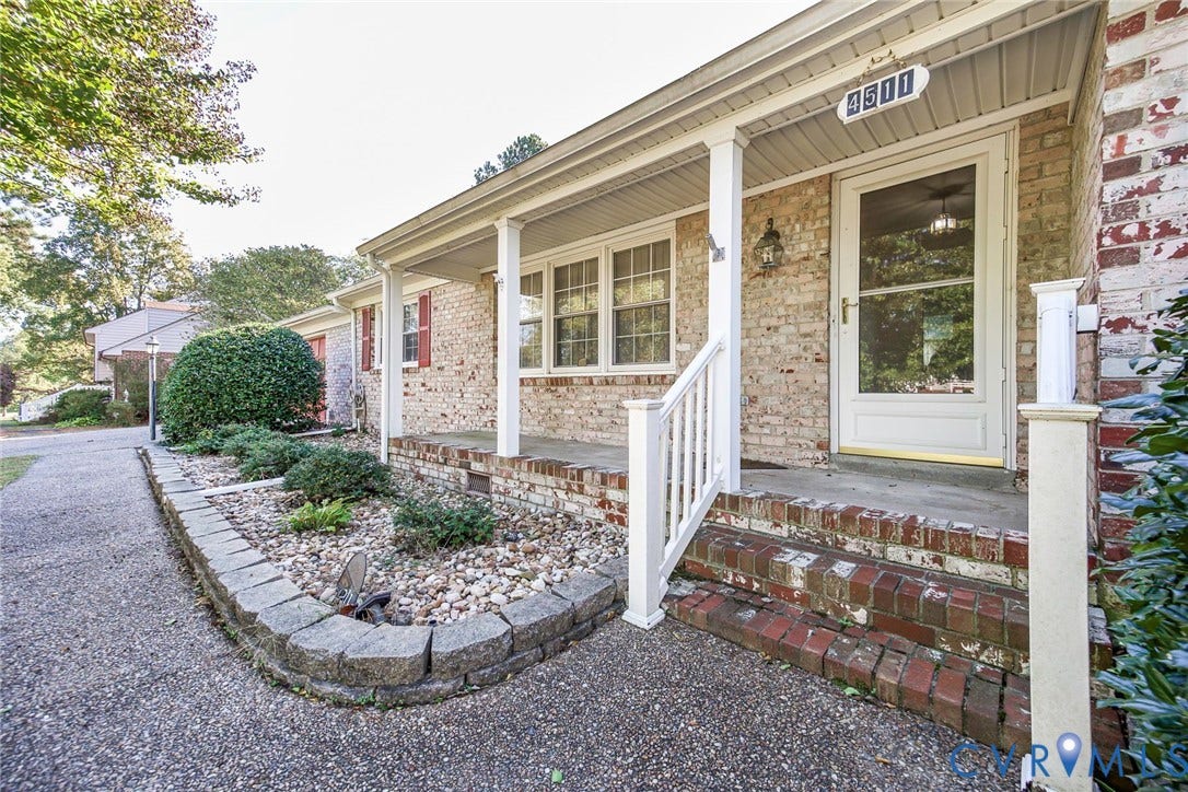 4511 Inca Drive, Ampthill, VA 23237 Brick exterior facade featuring a covered front porch, stone-retained landscaping bed, multi-pane windows with shutters, and concrete walkway