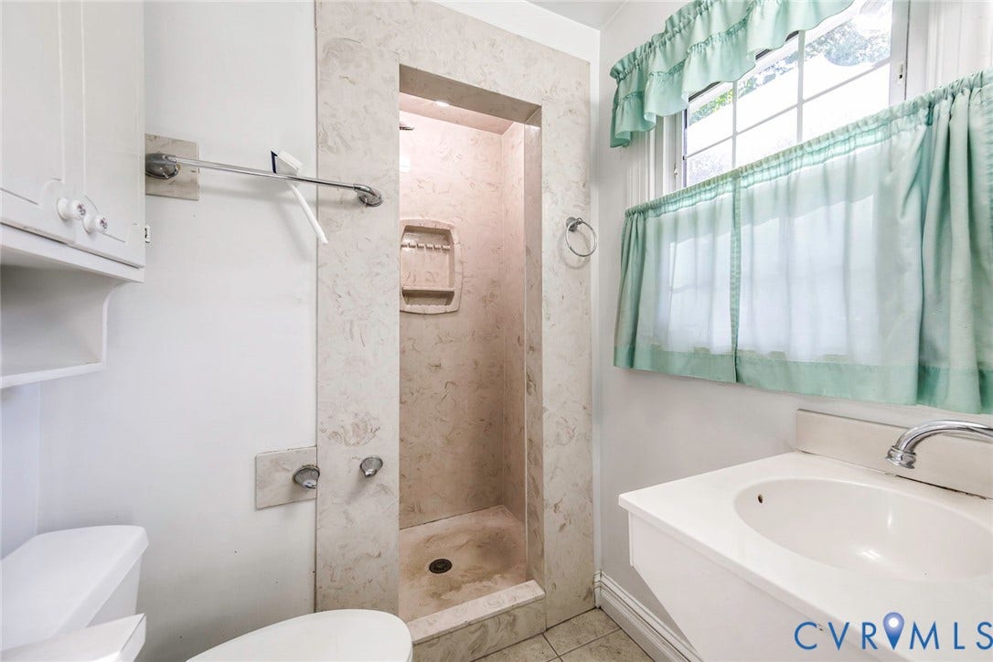 4511 Inca Drive, Ampthill, VA 23237 Walk-in shower featuring stone-tiled surround and built-in recessed niche, pedestal sink with integrated faucet, and custom-fit built-in cabinetry