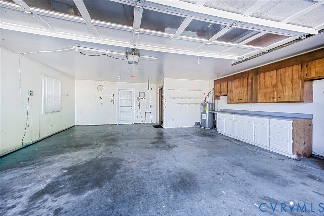 4511 Inca Drive, Ampthill, VA 23237 Multi-car garage featuring built-in wood cabinetry, integrated workspace countertops, and overhead garage door track system