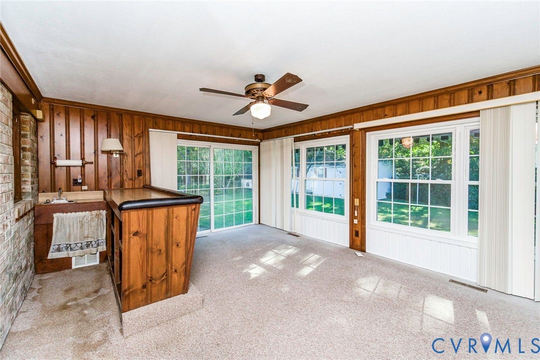 4511 Inca Drive, Ampthill, VA 23237 Wood-paneled room featuring a built-in wet bar, large windows with white trim, a ceiling fan, and sliding glass doors