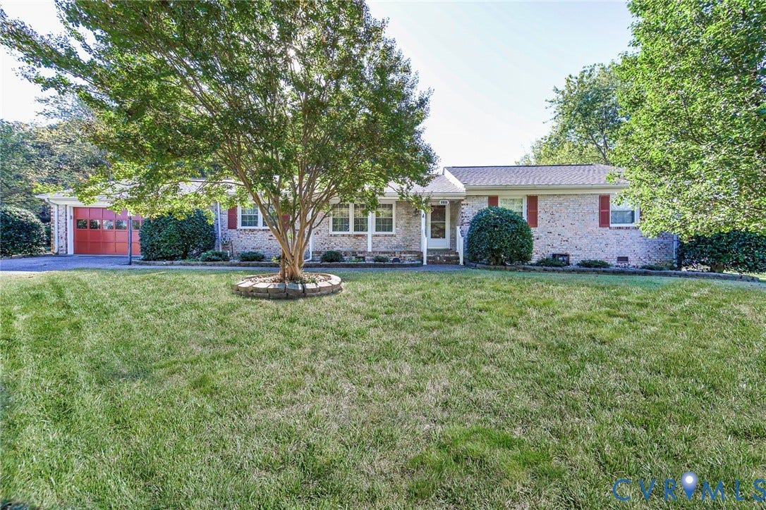 4511 Inca Drive, Ampthill, VA 23237 Single-story brick exterior featuring a multi-paneled garage door, shuttered windows, and a stone-bordered tree planter