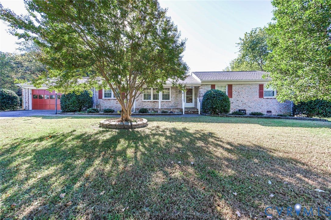 4511 Inca Drive, Ampthill, VA 23237 Single-story brick exterior featuring red shutters, attached garage, stone-bordered tree planter, and expansive front lawn