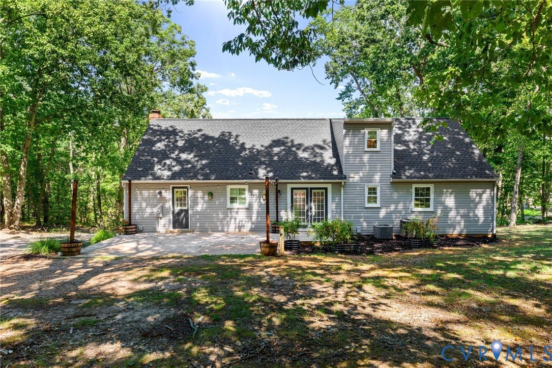 2137 Scarlet Mill Lane, Powhatan, VA 23139 Two-story residence featuring light-colored horizontal siding, asphalt shingle roofing, a paved patio, and double glass-paneled exterior doors