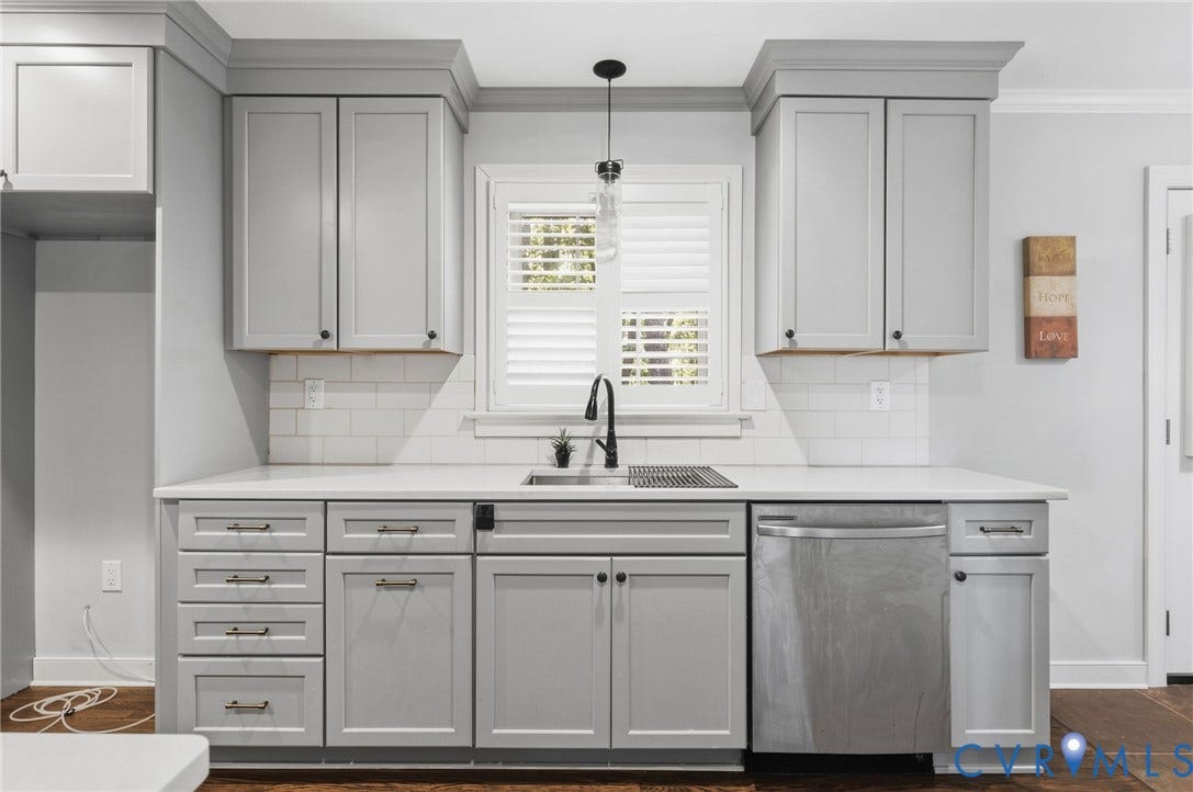 2137 Scarlet Mill Lane, Powhatan, VA 23139 Kitchen featuring shaker-style cabinetry with crown molding, white subway tile backsplash, solid-surface countertops, undermount stainless steel sink with matte black pull-down faucet, and plantation shutters