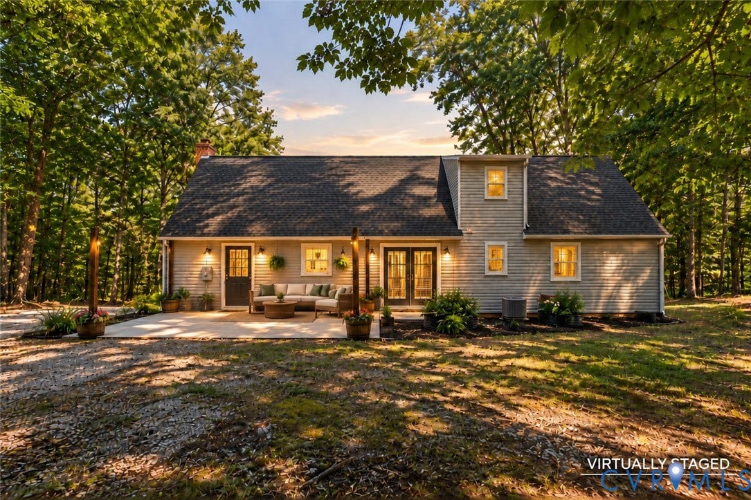 2137 Scarlet Mill Lane, Powhatan, VA 23139 Exterior featuring light-colored horizontal siding, a gabled roofline, concrete patio, and dual glass-paneled entry doors, set against a wooded landscape