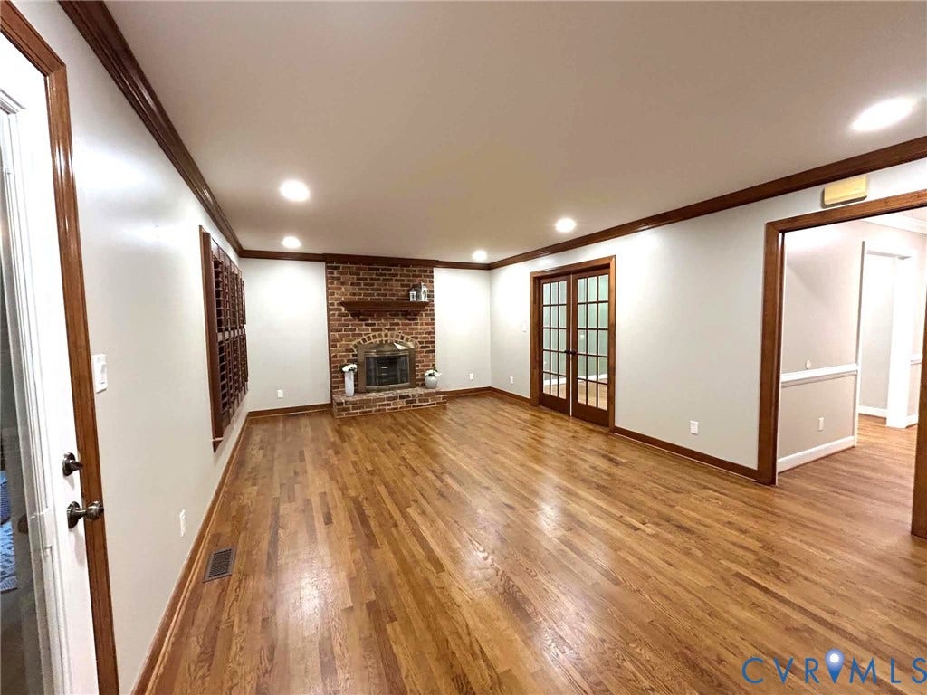 2255 Oak Bay Lane, Henrico, VA 23233 Hardwood flooring, brick fireplace with a mantel, crown molding, and French doors featuring multi-pane glass inserts