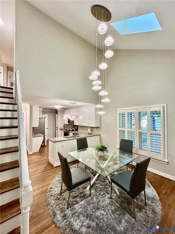 2255 Oak Bay Lane, Henrico, VA 23233 Vaulted ceilings featuring a multi-pendant light fixture and skylight, wood-finish flooring, staircase with white railing, and interior shutter window treatments