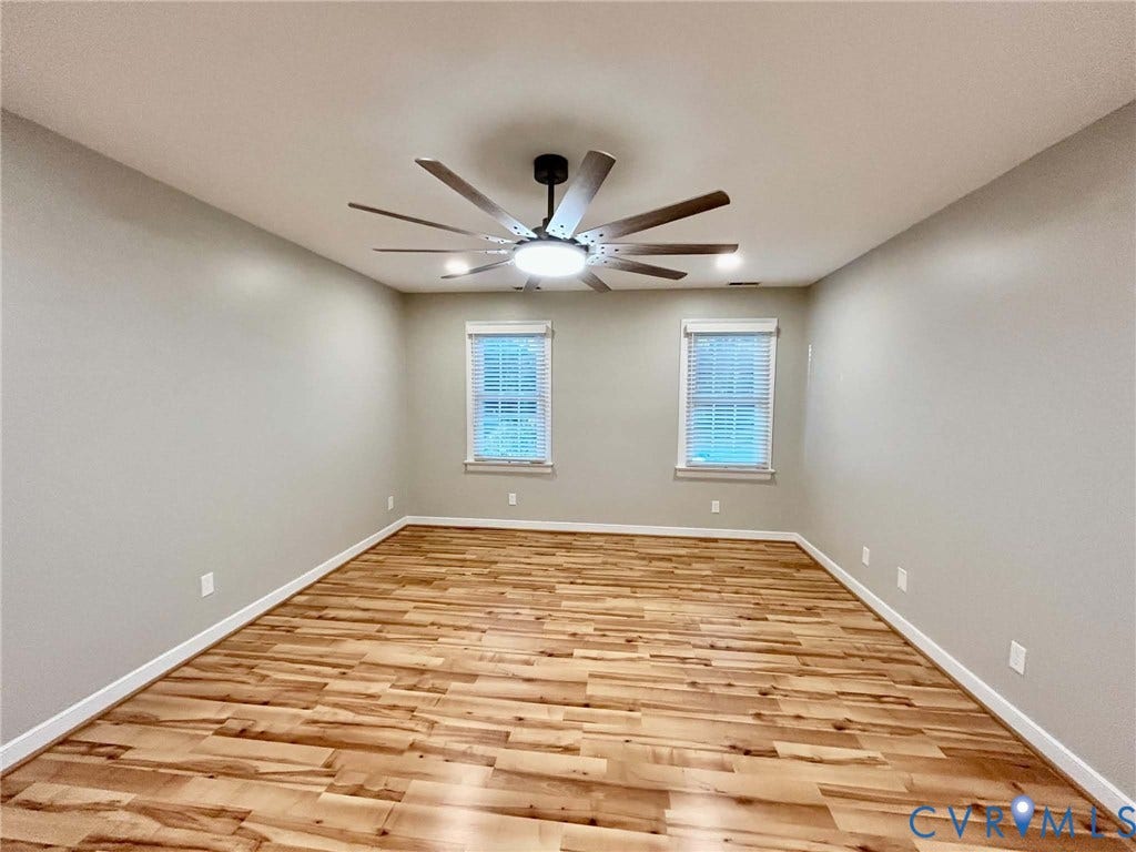 2255 Oak Bay Lane, Henrico, VA 23233 Neutral-toned room featuring wood-finish flooring, dual windows with integrated blinds, and a multi-blade ceiling fan with centered lighting
