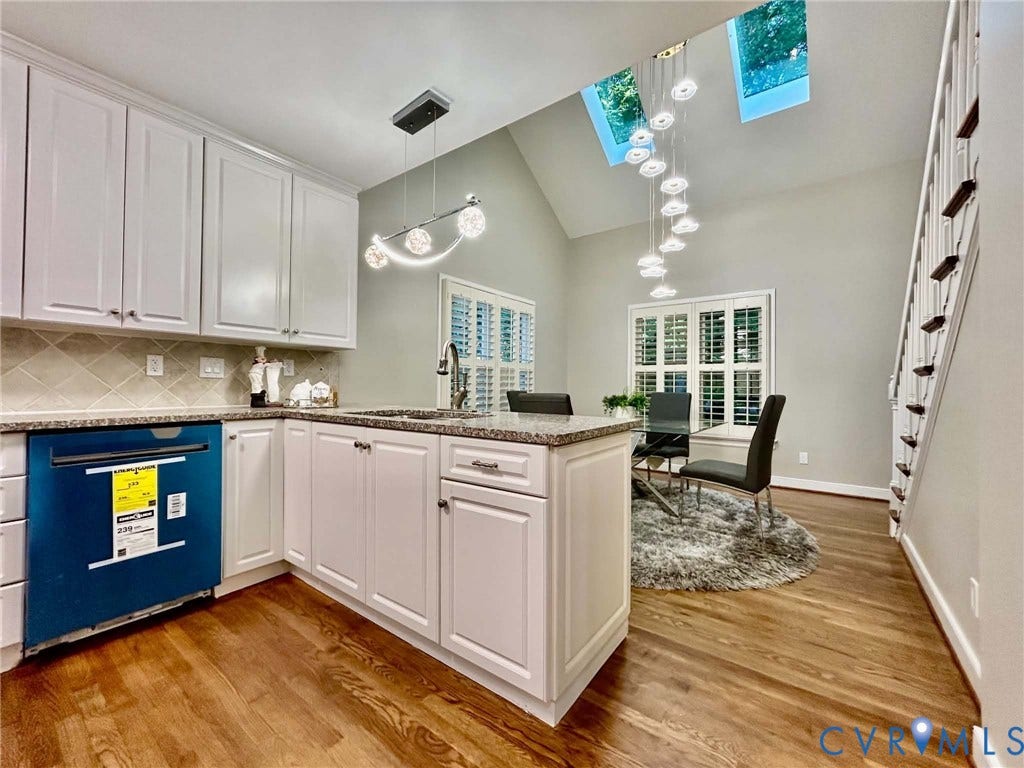 2255 Oak Bay Lane, Henrico, VA 23233 Kitchen featuring white cabinetry, stone-surface countertops, dual skylights, wood-finish flooring, and a multi-tiered decorative pendant light fixture
