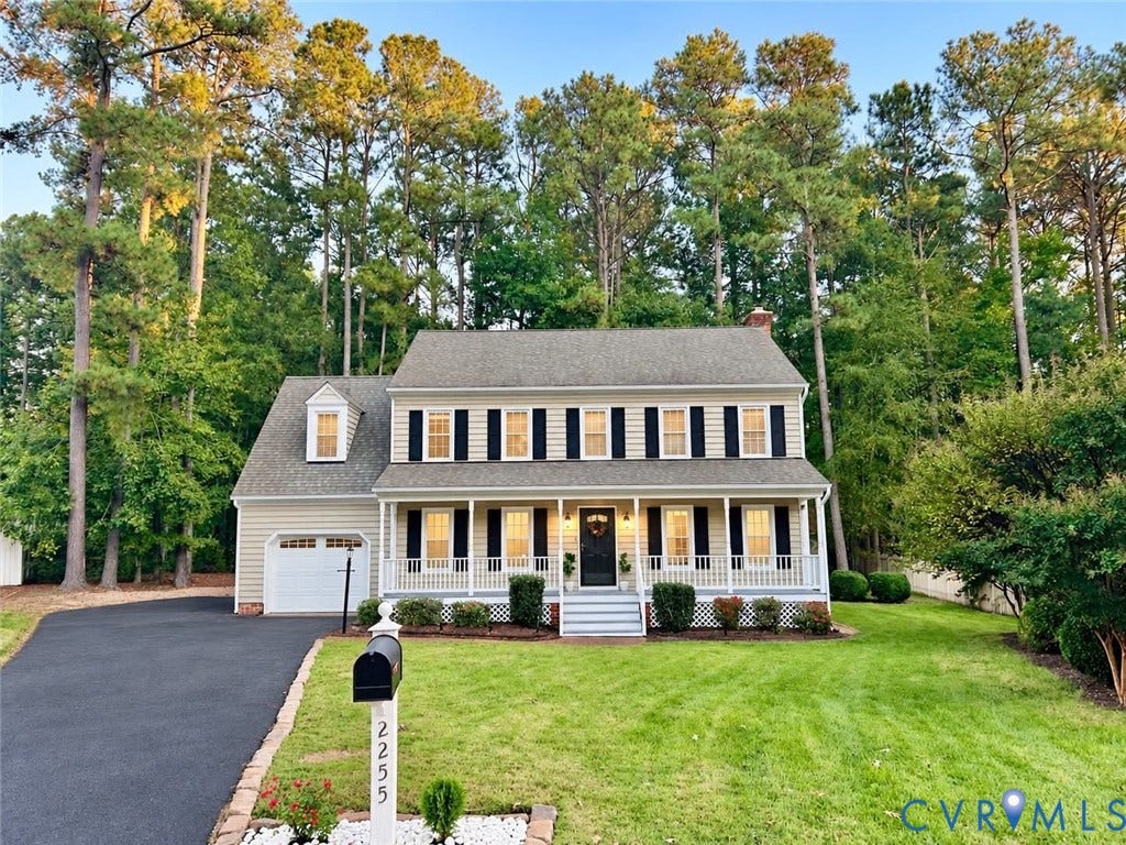 2255 Oak Bay Lane, Henrico, VA 23233 Colonial-style exterior featuring light-toned siding, a covered front porch with a white railing, black shutter accents, an attached garage, and a mature tree-lined perimeter