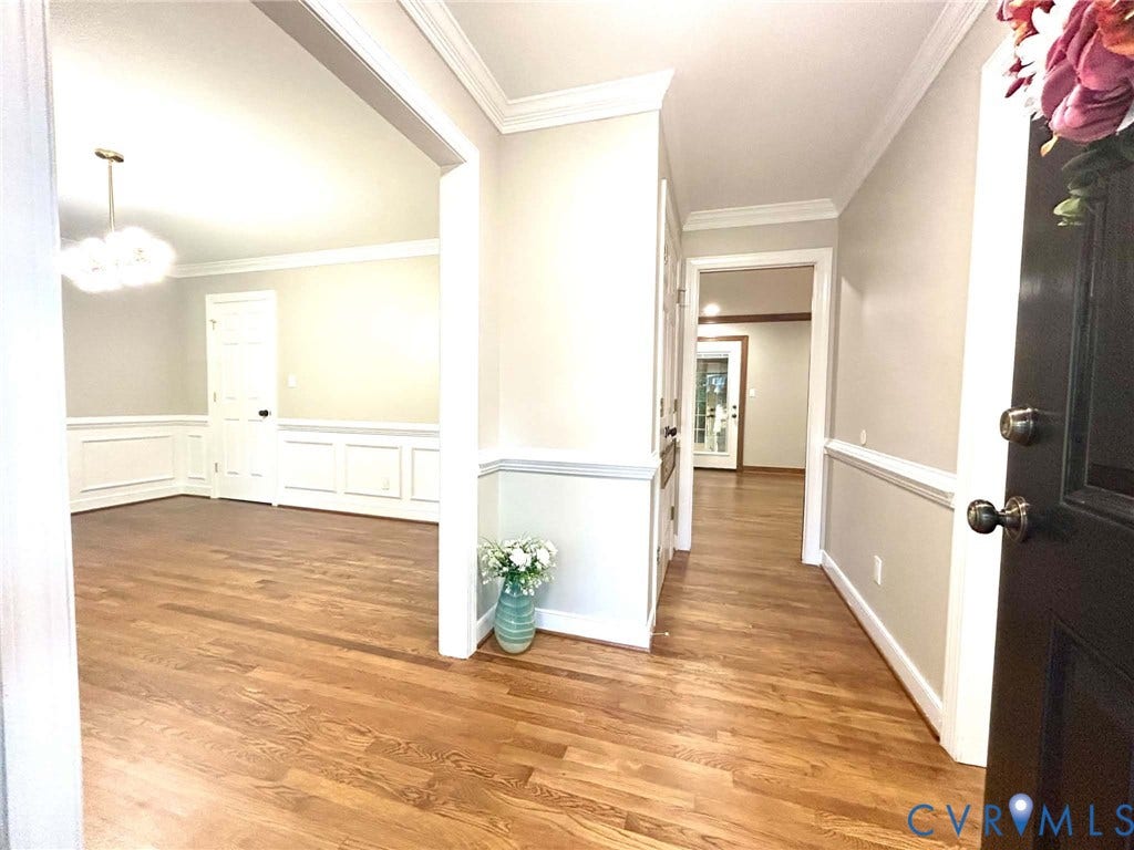 2255 Oak Bay Lane, Henrico, VA 23233 Entryway featuring wood-finish flooring, wainscoting, crown molding, a multi-light chandelier, and a solid-core entry door with metallic hardware