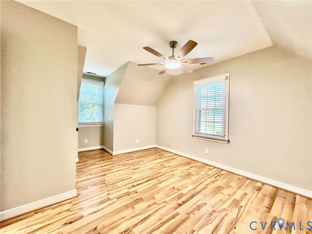 2255 Oak Bay Lane, Henrico, VA 23233 Vaulted ceiling featuring a central multi-blade ceiling fan with integrated lighting, wood-finish flooring, and dual windows with installed blinds