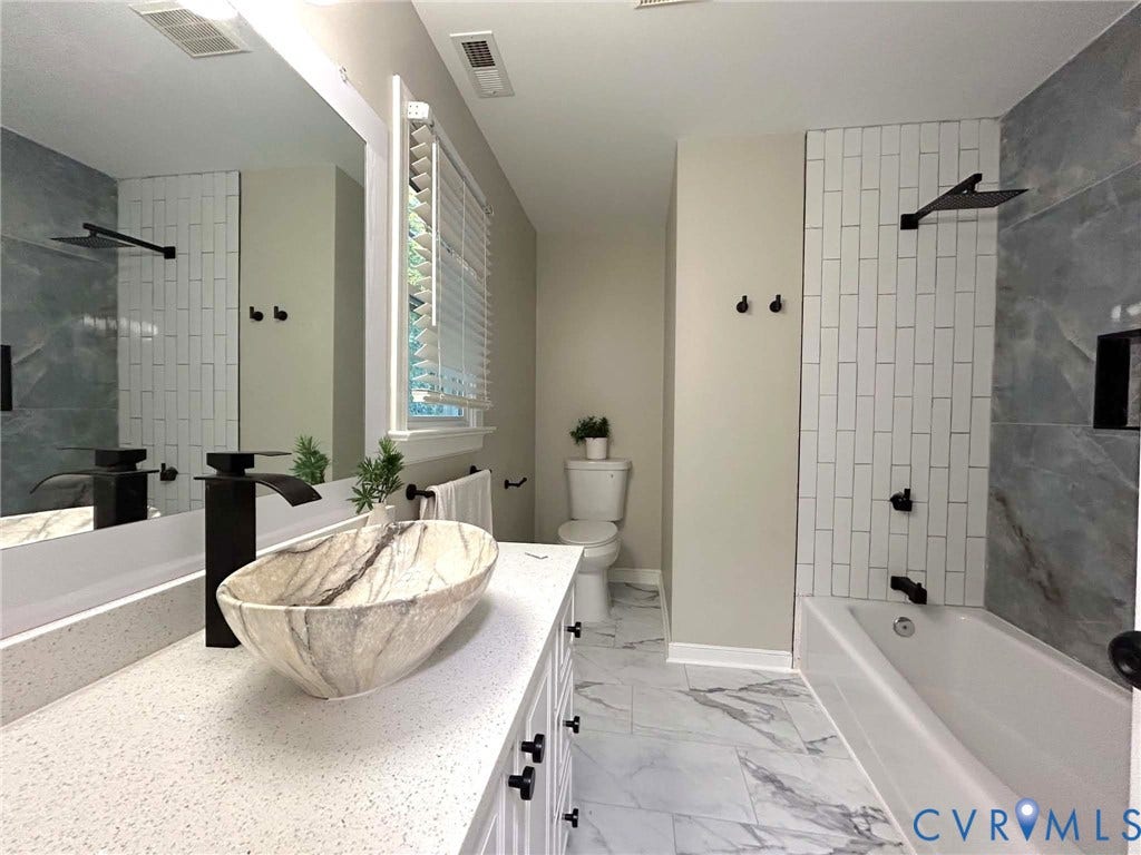 2255 Oak Bay Lane, Henrico, VA 23233 Bathroom featuring a vessel sink with a matte black faucet, light-toned countertop, vertical white subway tile tub surround, and patterned flooring