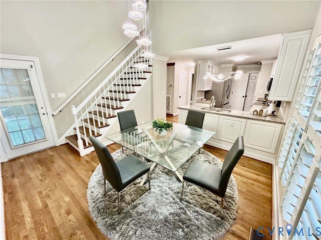 2255 Oak Bay Lane, Henrico, VA 23233 Open-concept floor plan with wood-finish flooring, vaulted ceilings, a staircase with white-finish banisters, built-in kitchen cabinetry, and multi-tier pendant lighting