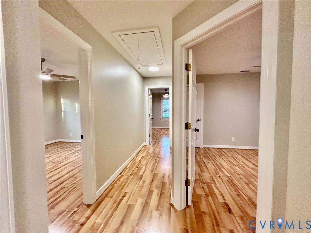 2255 Oak Bay Lane, Henrico, VA 23233 Interior hallway featuring wood-finish flooring, neutral wall paint, and multiple white-paneled interior doors