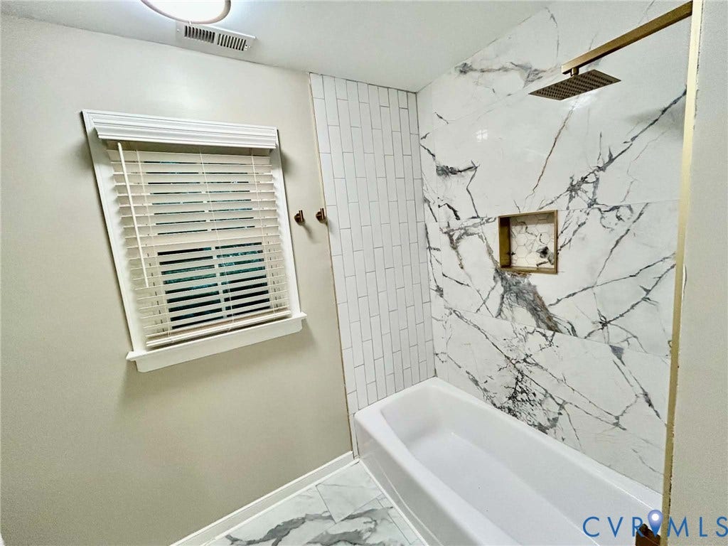 2255 Oak Bay Lane, Henrico, VA 23233 Bathtub surround featuring large-format stone-patterned tile, a recessed niche, vertical subway tile accents, and a gold-tone rainfall showerhead