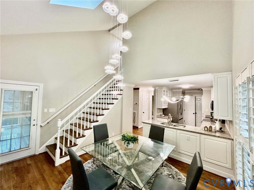 2255 Oak Bay Lane, Henrico, VA 23233 Vaulted ceiling featuring a tiered multi-light pendant fixture, wood-finish flooring, and a staircase with white painted balusters and wood-finish treads