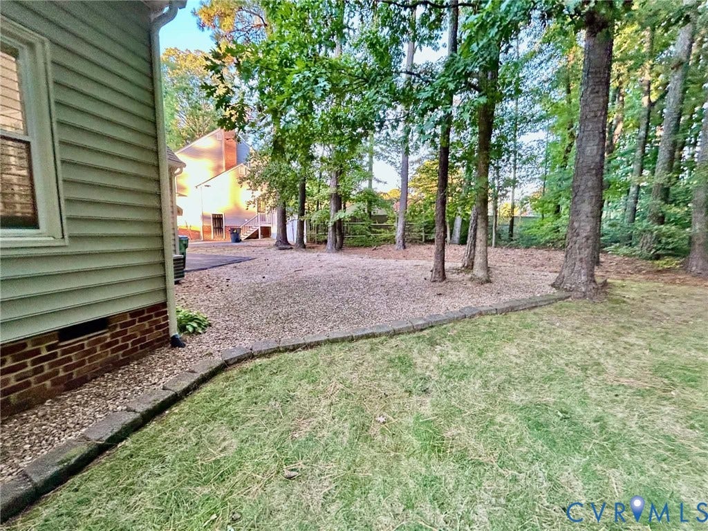 2255 Oak Bay Lane, Henrico, VA 23233 Exterior features include horizontal siding, a brick foundation, gravel ground cover, and mature trees
