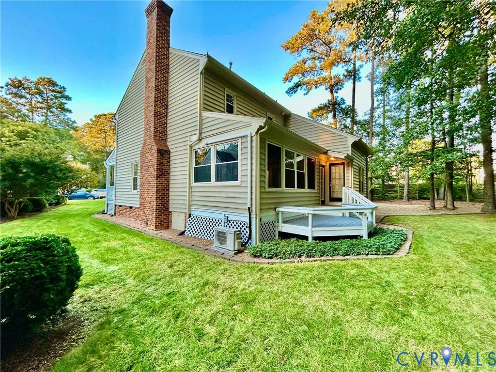 2255 Oak Bay Lane, Henrico, VA 23233 Exterior featuring light-colored horizontal siding, a full-height brick chimney, an elevated wooden deck, and manicured landscaping
