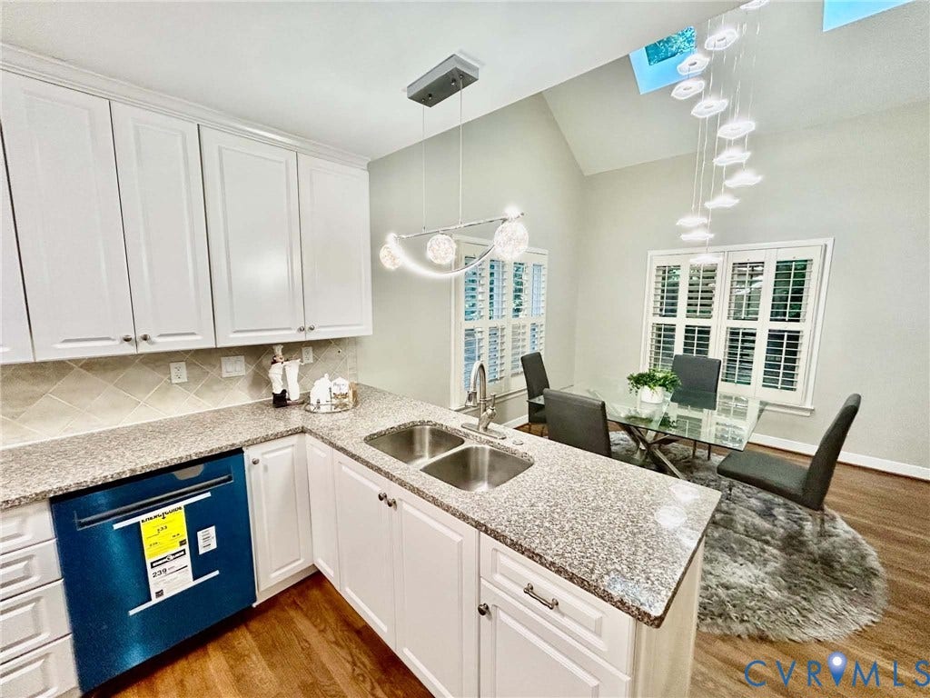 2255 Oak Bay Lane, Henrico, VA 23233 Kitchen featuring white shaker-style cabinetry, stone-finish countertops, stainless steel dual-basin undermount sink, vaulted ceiling with integrated skylights, and polished metal pendant lighting
