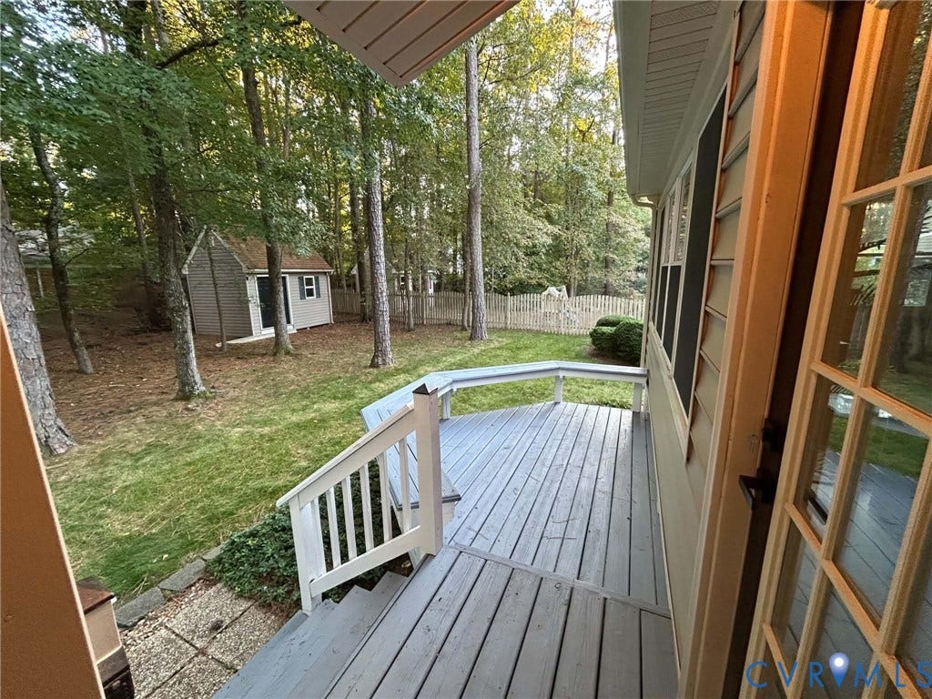 2255 Oak Bay Lane, Henrico, VA 23233 Elevated wood-plank deck featuring built-in bench seating, white railing, mature trees, and an exterior storage structure