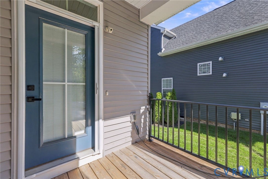 1716 German School Road, Westlake Heights, Richmond, VA 23225 Covered porch featuring wood-plank decking, metal railing, and a blue exterior door with a glass-paneled storm door