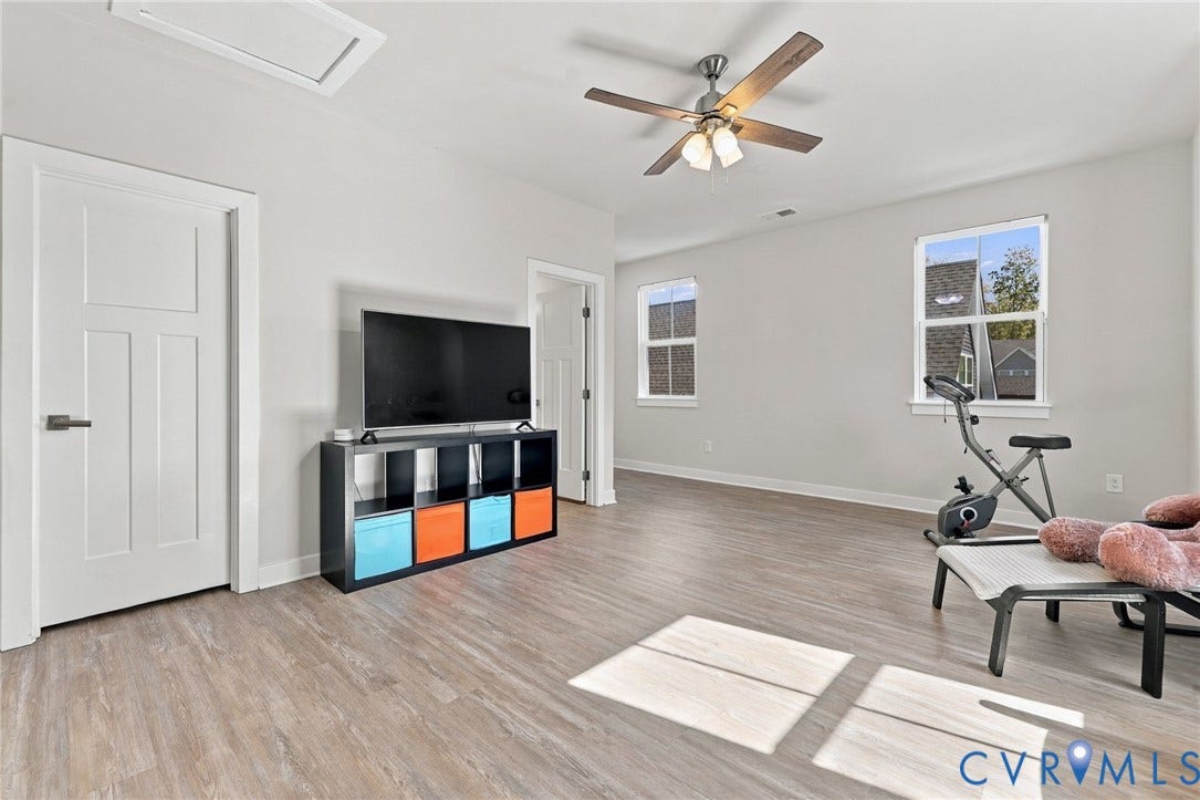 1716 German School Road, Westlake Heights, Richmond, VA 23225 Neutral-toned room featuring wood-finish flooring, a ceiling fan with integrated lighting, and multi-pane windows