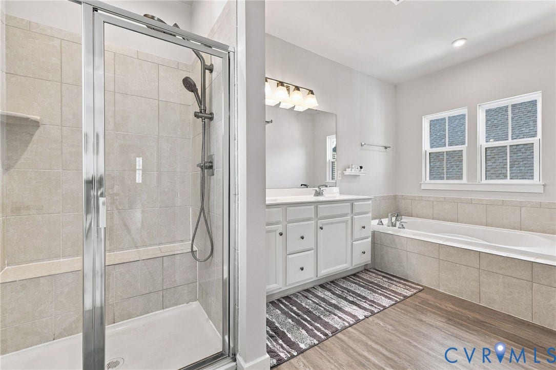 1716 German School Road, Westlake Heights, Richmond, VA 23225 Bathroom featuring a tiled glass-enclosed shower, soaking tub with tile surround, white cabinetry, wood-finish flooring, and multi-light vanity fixture