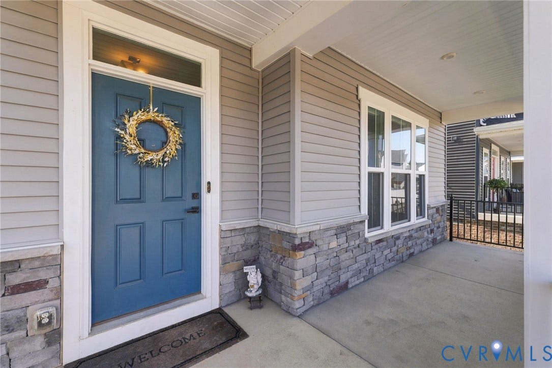 1716 German School Road, Westlake Heights, Richmond, VA 23225 Covered front porch featuring horizontal lap siding, stacked stone veneer wainscoting, a paneled door with a transom window, and integrated recessed lighting