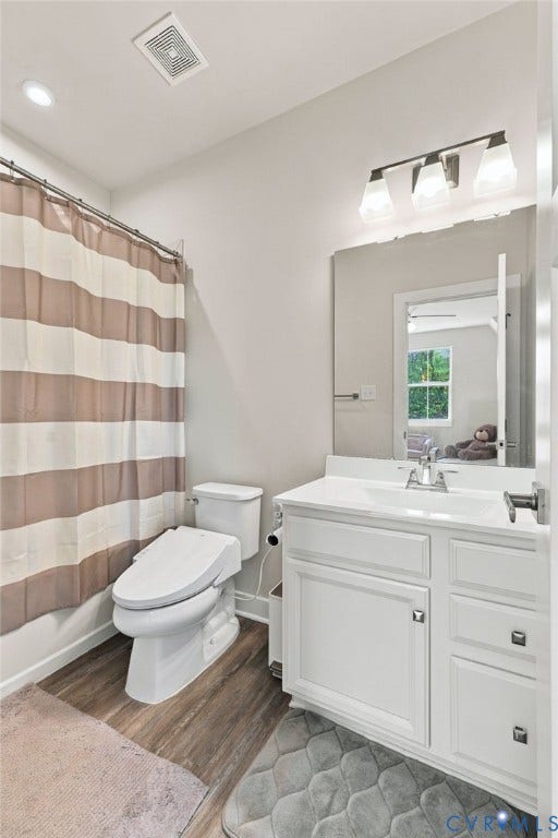 1716 German School Road, Westlake Heights, Richmond, VA 23225 Bathroom featuring a white vanity cabinet with a integrated sink, wood-finish flooring, and a three-light wall-mounted fixture above a rectangular mirror