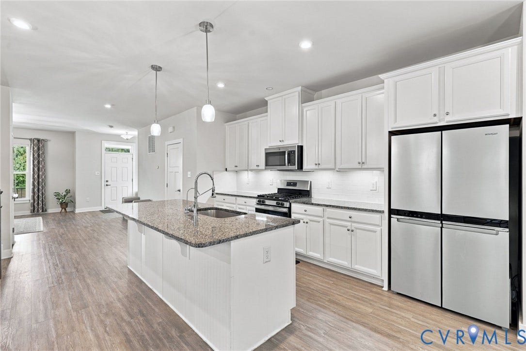 1716 German School Road, Westlake Heights, Richmond, VA 23225 Kitchen featuring white cabinetry, stone-finish countertops, a center island with an integrated sink, stainless steel appliances, and wood-finish flooring