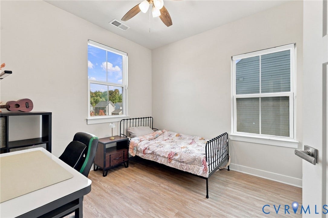 1716 German School Road, Westlake Heights, Richmond, VA 23225 Neutral-toned interior space featuring wood-finish flooring, dual windows with white frames, and a ceiling fan with light fixture