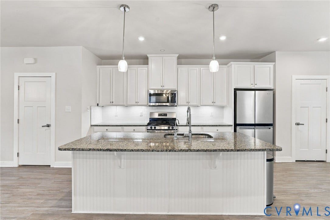 1716 German School Road, Westlake Heights, Richmond, VA 23225 Kitchen featuring white shaker-style cabinetry, stone-finish countertops, a center island with beadboard detailing, stainless steel appliances, and dual pendant lighting