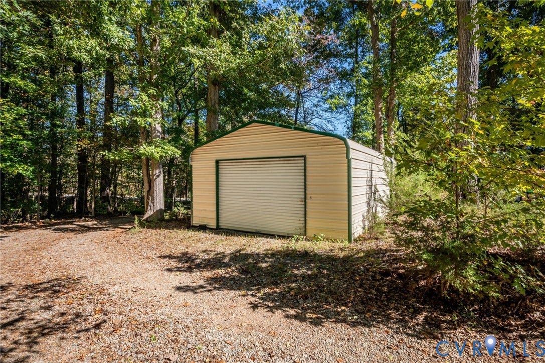 2790 Maidens Road, Powhatan, VA 23139 Detached metal storage structure featuring a roll-up door, corrugated siding, and gravel ground surfacing. At front corner of the property and sits away from the house.