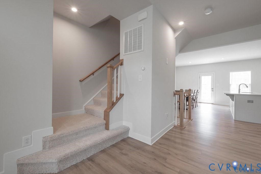 10221 Wenden Way, Hanover, VA 23005 Staircase featuring carpeted steps, a wooden handrail, and white balusters, finished with wood-finish flooring and recessed lighting