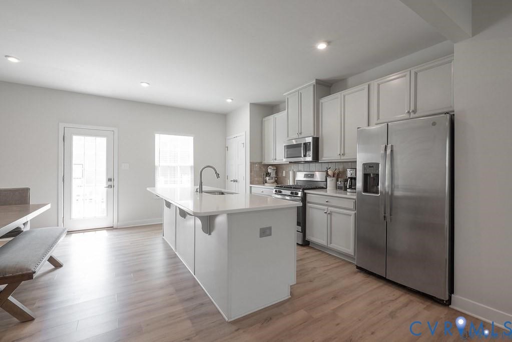 10221 Wenden Way, Hanover, VA 23005 Kitchen featuring wood-finish flooring, white cabinetry, a center island with a stone-surface countertop, and stainless steel appliances