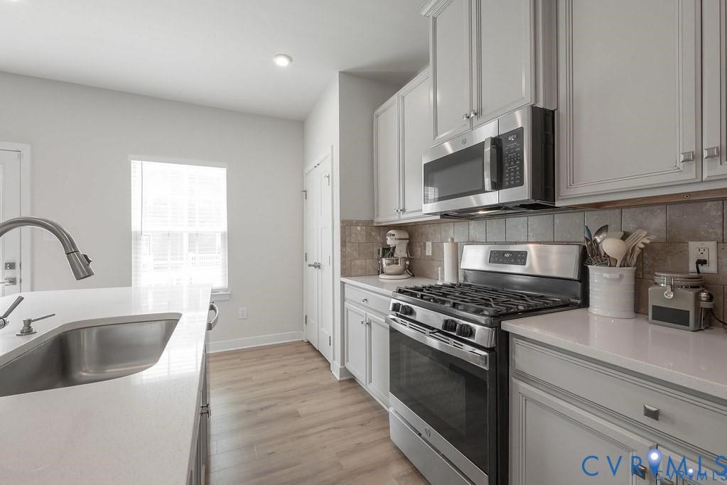 10221 Wenden Way, Hanover, VA 23005 Kitchen featuring shaker-style cabinetry, quartz countertops, tile backsplash, stainless steel appliances, and wood-finish flooring