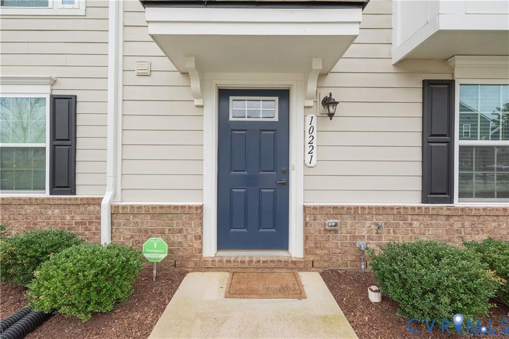 10221 Wenden Way, Hanover, VA 23005 Entrance featuring a navy-painted door with transom window, lap siding, brick facade accents, and decorative window shutters