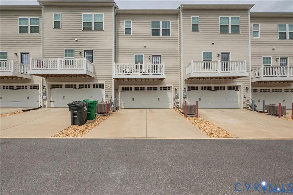 10221 Wenden Way, Hanover, VA 23005 Multi-level townhome exterior featuring light-toned horizontal siding, private raised decks with white railings, concrete driveways, and two-car attached garages
