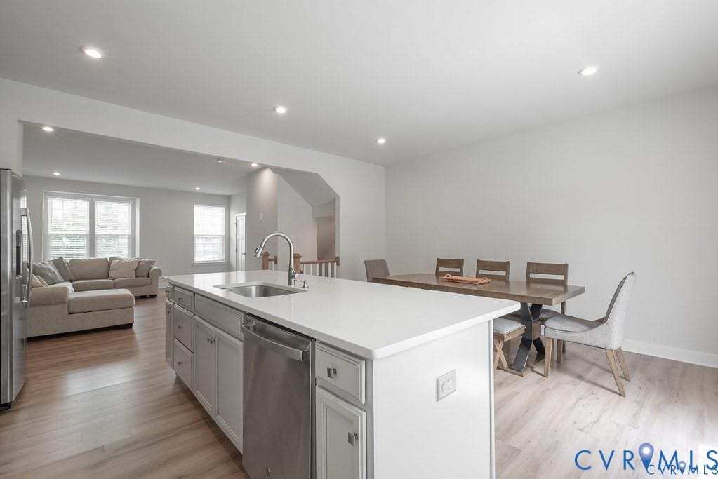 10221 Wenden Way, Hanover, VA 23005 Kitchen featuring a central island with white cabinetry, light-toned stone-finish countertop, stainless steel dishwasher, and a gooseneck faucet, set against wood-finish flooring and recessed lighting