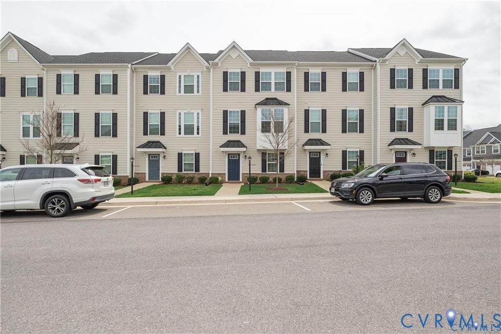 10221 Wenden Way, Hanover, VA 23005 Multi-story townhome exterior featuring neutral vinyl siding, dark shutters, bay windows, gabled rooflines, and individual covered entryways