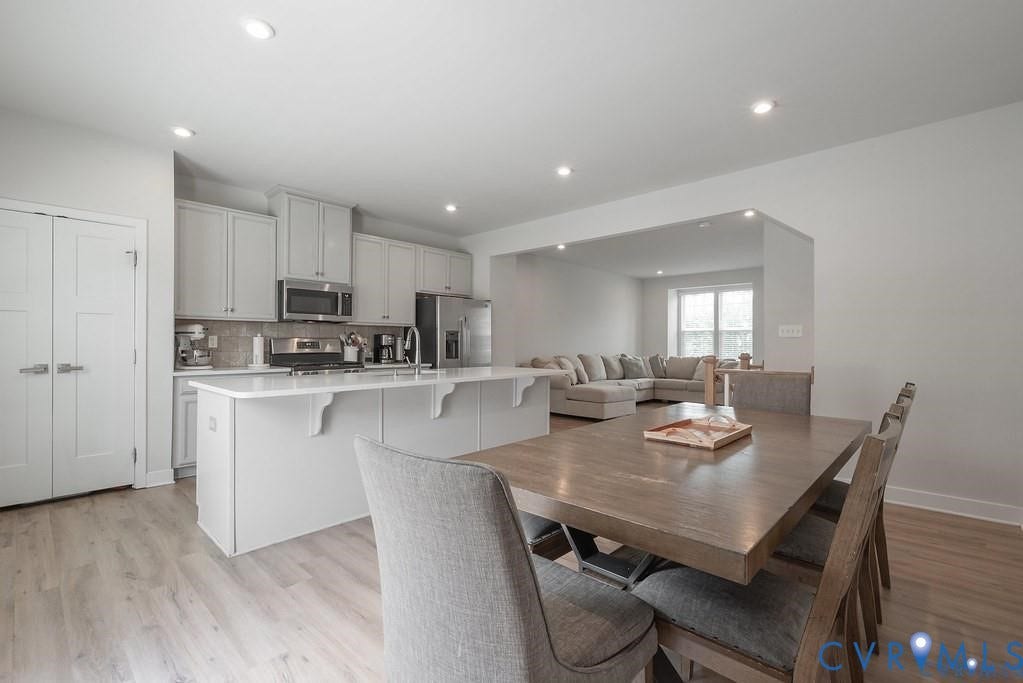 10221 Wenden Way, Hanover, VA 23005 Kitchen featuring white cabinetry, an expansive island with a countertop, stainless steel appliances, and wood-finish flooring