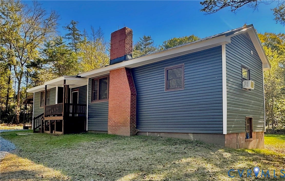 15051 BENT CREEK ROAD, Morven, Amelia, VA 23002 Exterior featuring dark horizontal siding, a prominent exposed red brick chimney, and a raised wooden porch with railings