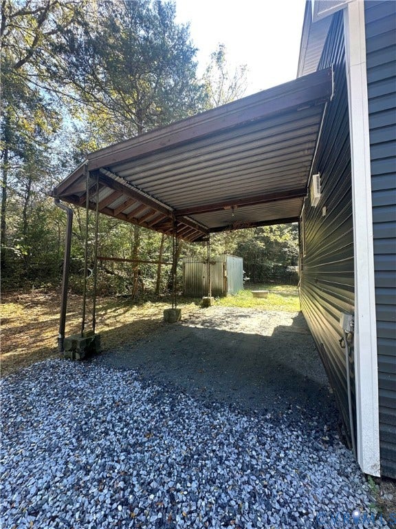 15051 BENT CREEK ROAD, Morven, Amelia, VA 23002 Attached carport featuring a metal roof, dark horizontal siding, and gravel ground surfacing